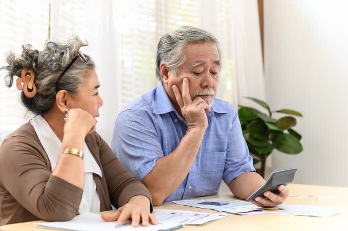 Two visibly worried people reviewing invoices and financial statements while sitting at a table.