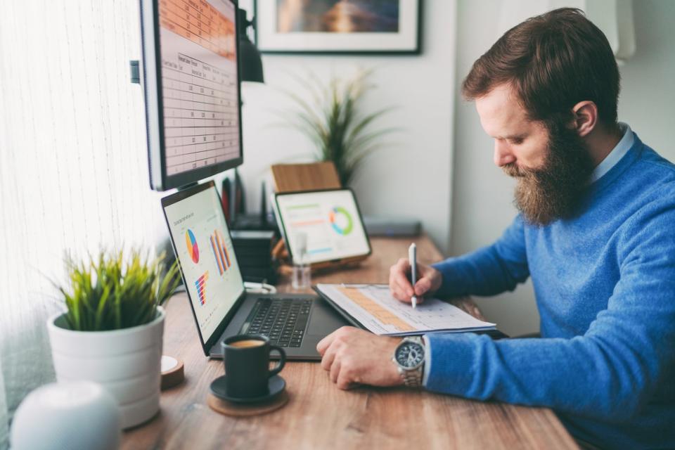 Person looking at charts on computer and writing notes.