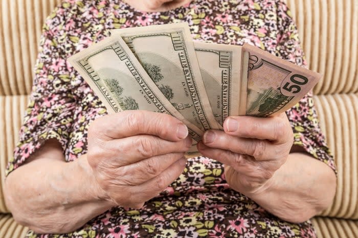 A seated person counting a pile of assorted money bills in his hands. 